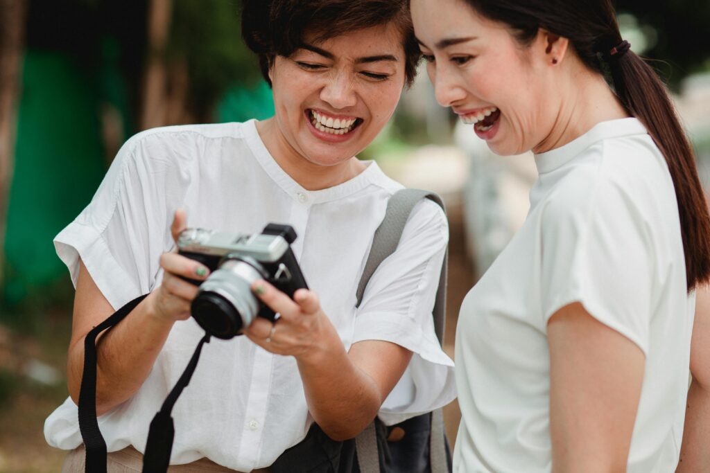 Woman embracing life after kids as photographer, showing off the photos on her camera to a friend