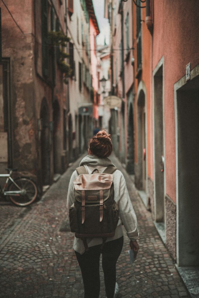 Woman with a backpack living abroad and exploring the narrow walkway between buildings.