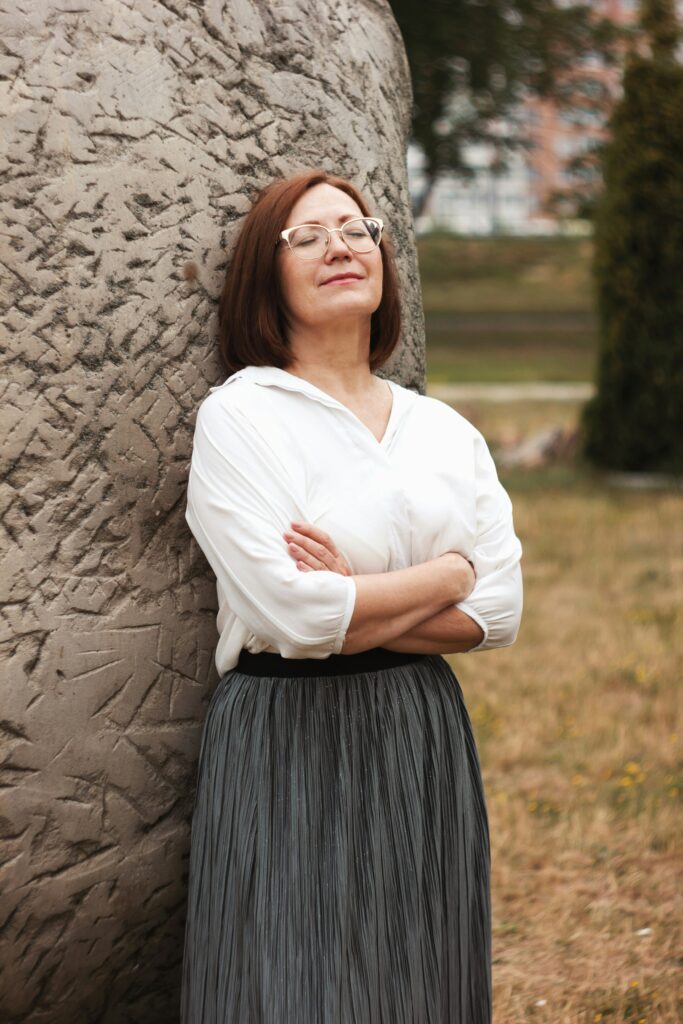 Woman with her eyes closed leaning against a tree feeling balanced.