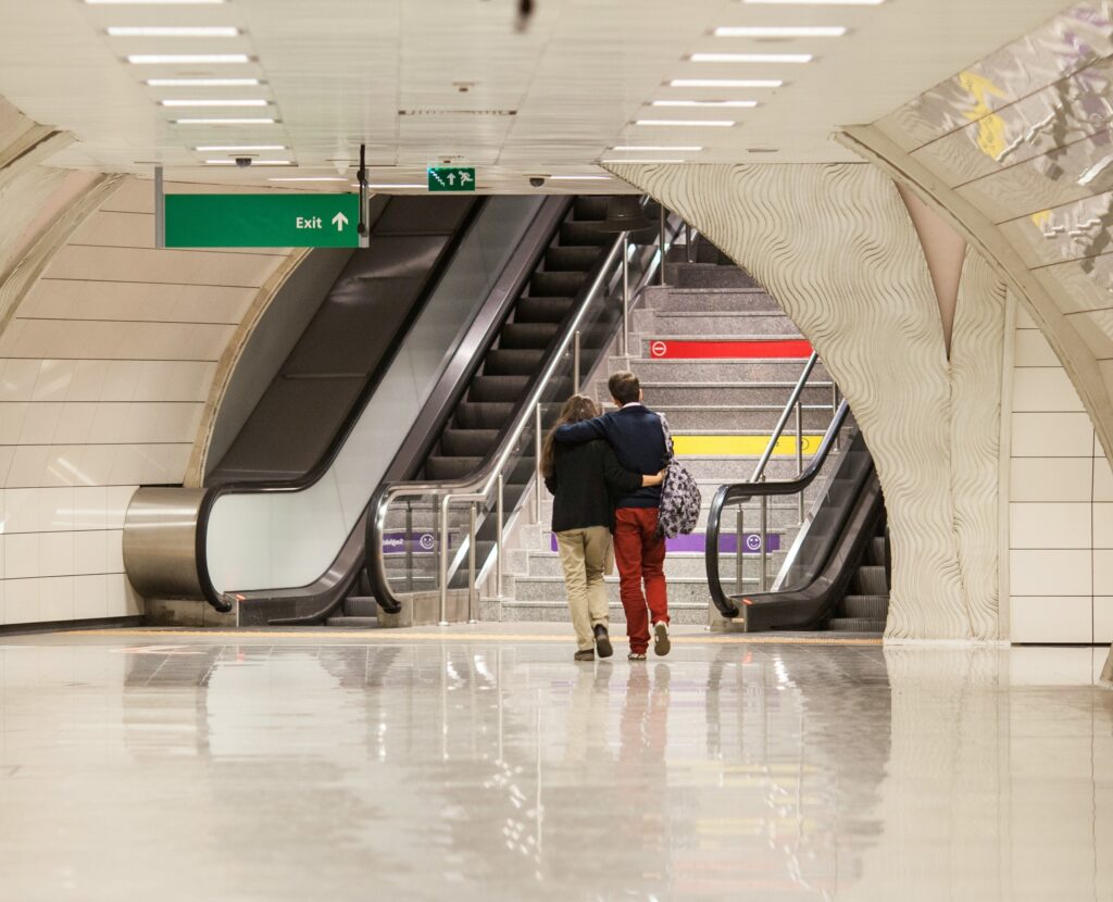 Couple approaching stairs to exit an airport on their journey to learn how to live abroad.